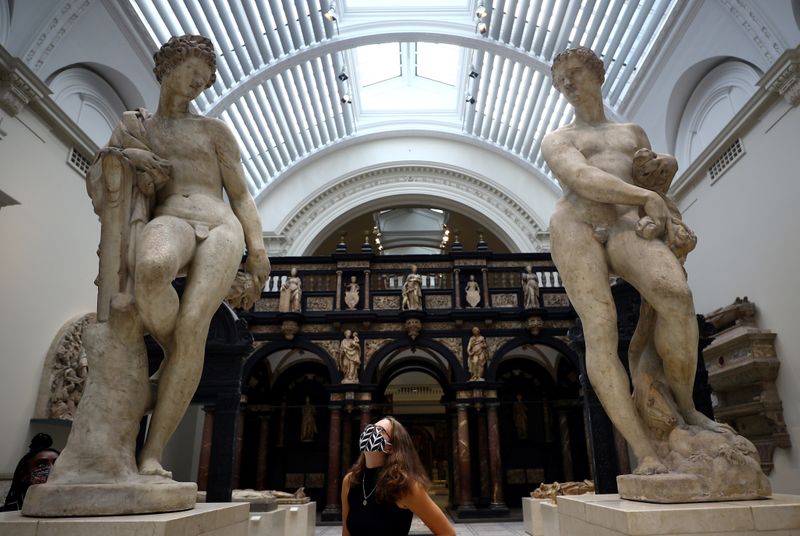 &copy; Reuters. A Victoria &amp; Albert (V&amp;A) Museum gallery assistant poses for members of the media in front of the Apollo and Zephyr sculptures by Pietro Francavilla during preparations to reopen the museum, in London