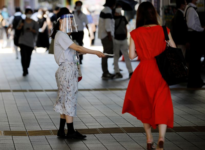 &copy; Reuters. A saleswoman wearing a face shield distributes leaflets on the street amid the coronavirus disease (COVID-19) pandemic in Tokyo