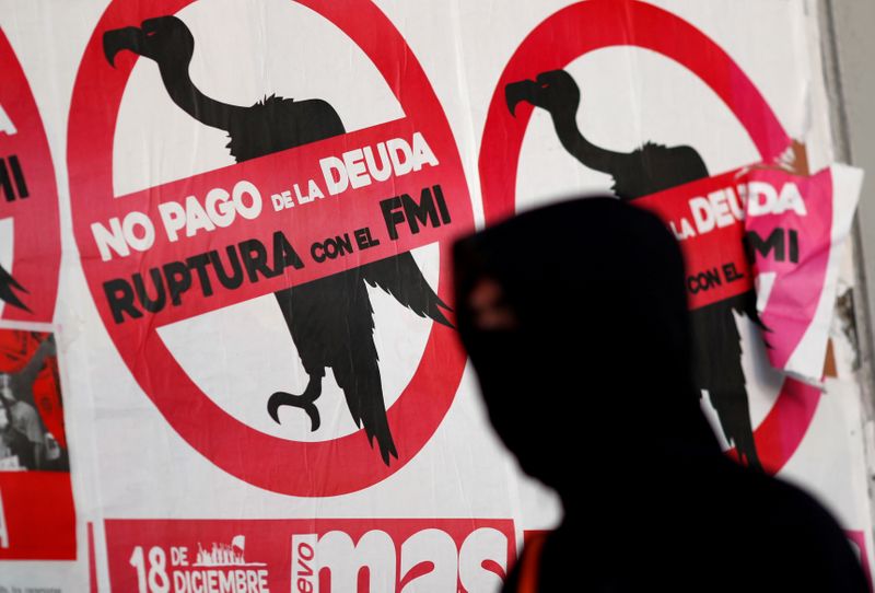 &copy; Reuters. FILE PHOTO: A pedestrian wearing a face mask walks past posters on the street that read &quot;No to the payment of the debt. Break with the IMF&quot;, in Buenos Aires