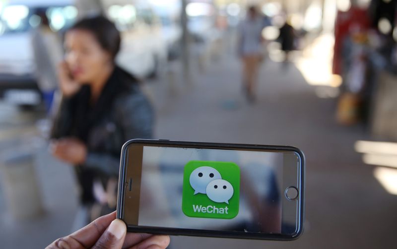 © Reuters. A WeChat logo is displayed on a mobile phone as a woman walks past as she talks on her mobile phone at a taxi rank in this picture illustration