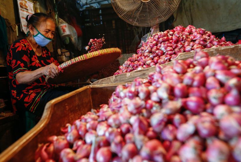 &copy; Reuters. A worker wearing a protective face mask sorts onion at a traditional market amid the spread of the coronavirus disease (COVID-19)