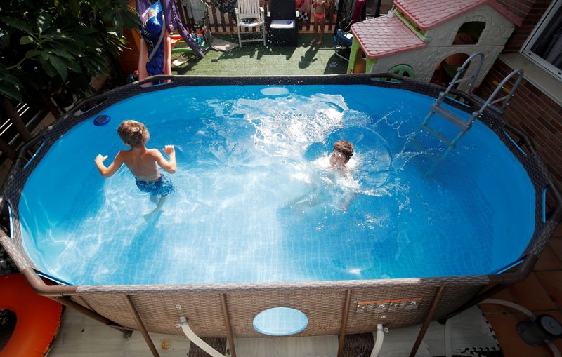 © Reuters. Albert and Gonzalo Cano Lapuente cool off in a Bestway Above Ground Pool in Premia de Mar