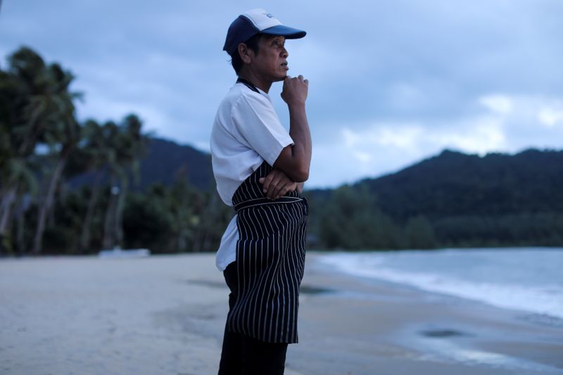 © Reuters. FILE PHOTO: A chef stands on an empty beach as he waits for the costumers at Koh Chang island in Thailand