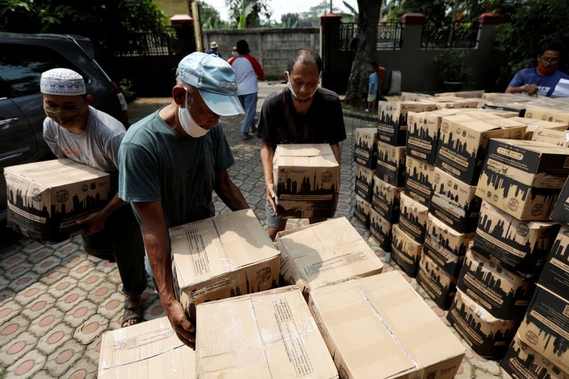 © Reuters. Volunteers prepare boxes of food aid to be distributed to the locals at a residential area in Jakarta