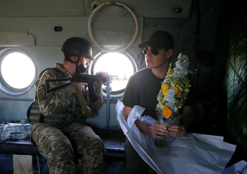 © Reuters. A Ukrainian presidential office official holds flowers inside a helicopter during President Zelenskiy's working trip in Donetsk Region