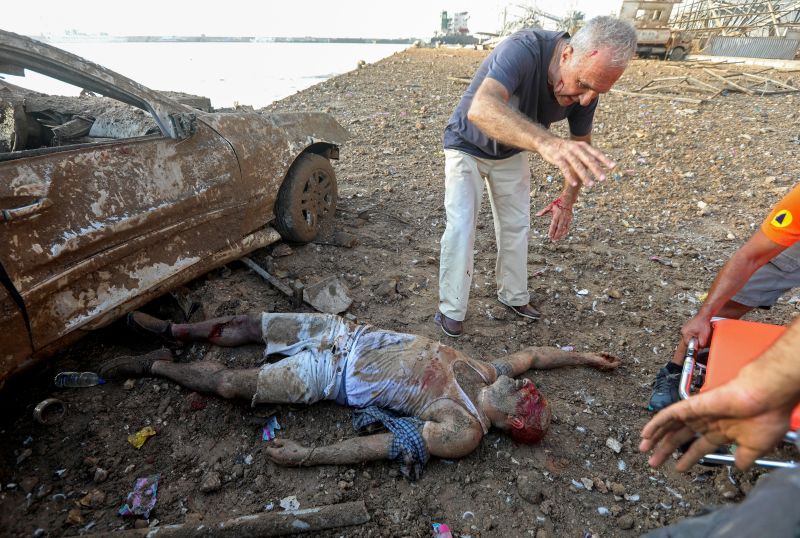 © Reuters. MATERIAL SENSIBLE. ESTA IMAGEN PUEDE LATIMAR O PERTURBAR: Un hombre herido que quedó atrapado debajo de un vehículo después de una explosión en el área portuaria de Beirut es ayudado por un grupo de personas. Líbano, 4 de agosto de 2020.