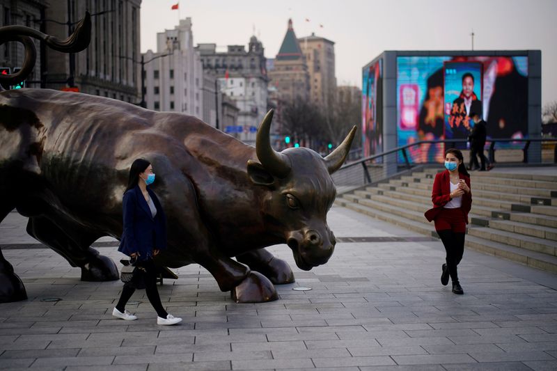 &copy; Reuters. Pedestrians wearing face masks walk near the Bund Financial Bull statue in Shanghai