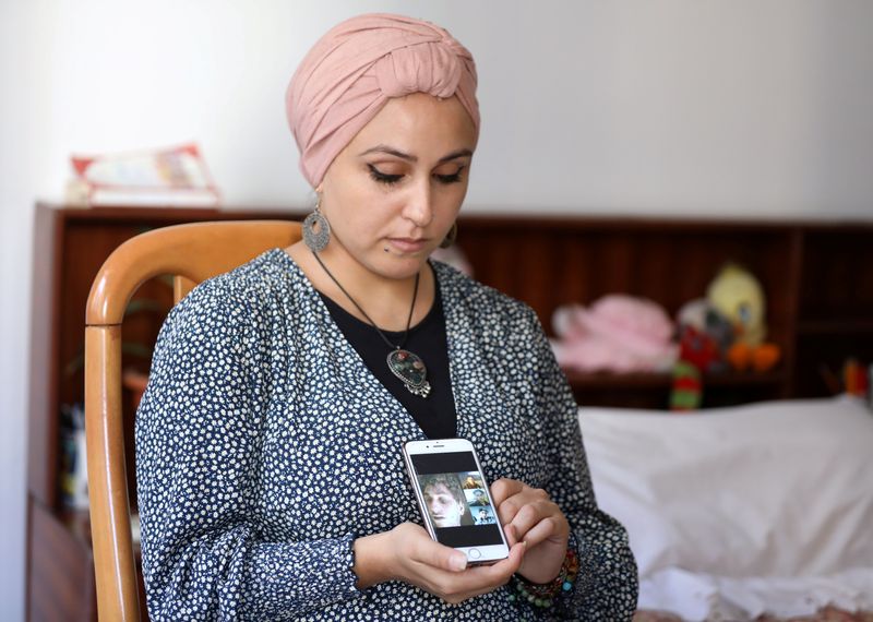 &copy; Reuters. Fida Al Waer, a Syrian artist and teacher living in Beirut, poses as she holds a mobile phone in Beirut