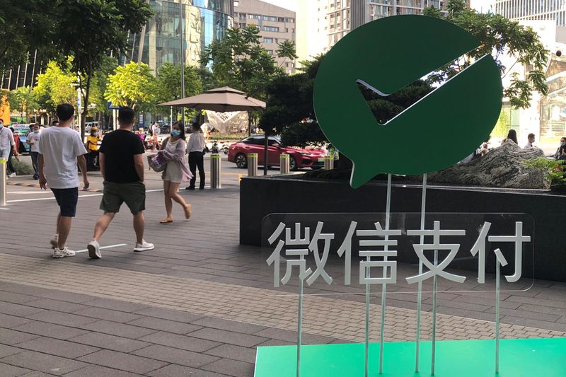 © Reuters. People walk past a Wechat Pay sign at the Tencent company headquarters in Shenzhen