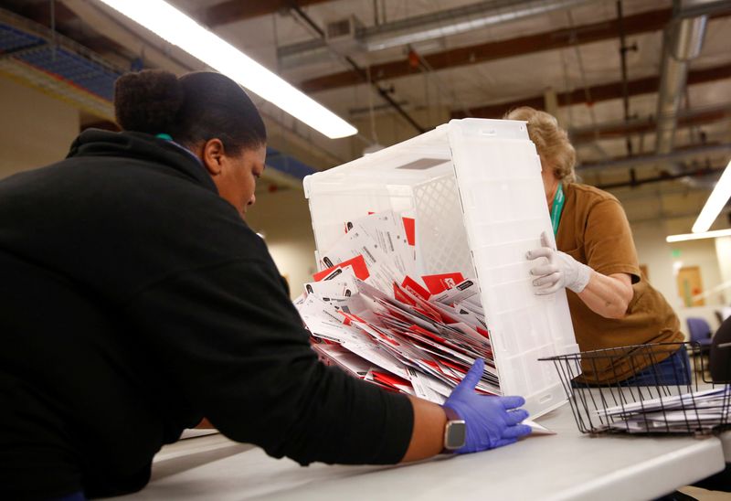 &copy; Reuters. FILE PHOTO: Workers empty a carton of ballots from a drop box to prepare them for the mail sorting machine during the presidential primary at King County Elections ballot processing center in Renton