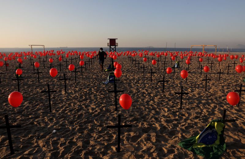 &copy; Reuters. Una persona entre las cruces y globos colocados por miembros de la ONG Río de Paz en homenaje a las cien mil víctimas mortales de la enfermedad COVID-19 en el país, en la playa de Copacabana en Río de Janeiro
