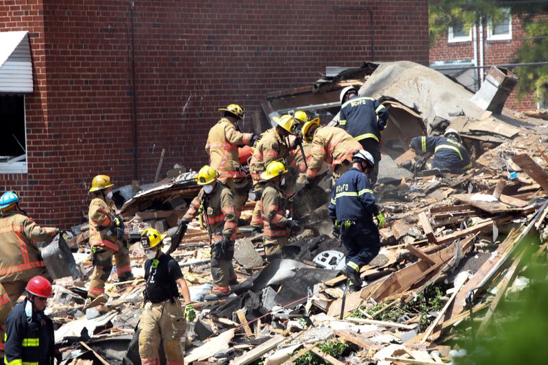 © Reuters. Rescue workers stand on the debris of a destroyed building after an explosion in a residential area of Baltimore