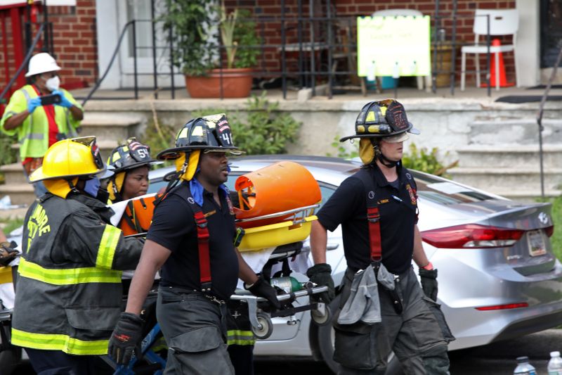 © Reuters. Fire fighters transport an injured person on a stretcher at the scene of an explosion in a residential area of Baltimore