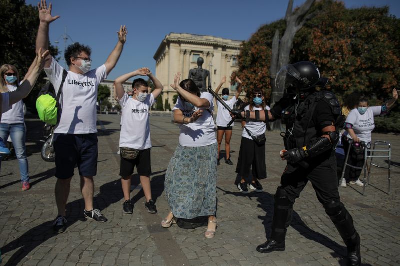 &copy; Reuters. Activist Marian Raduna, dressed as a riot police officer, pretends to hit a woman wearing a white shirt with the text &quot;Romanian Diaspora\