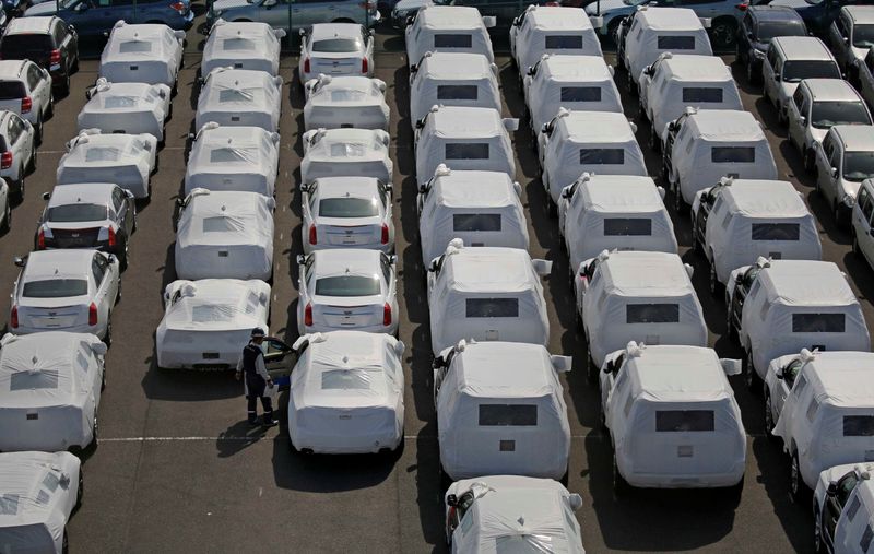 &copy; Reuters. A man works among imported cars covered with a white cloth in a port in Yokohama