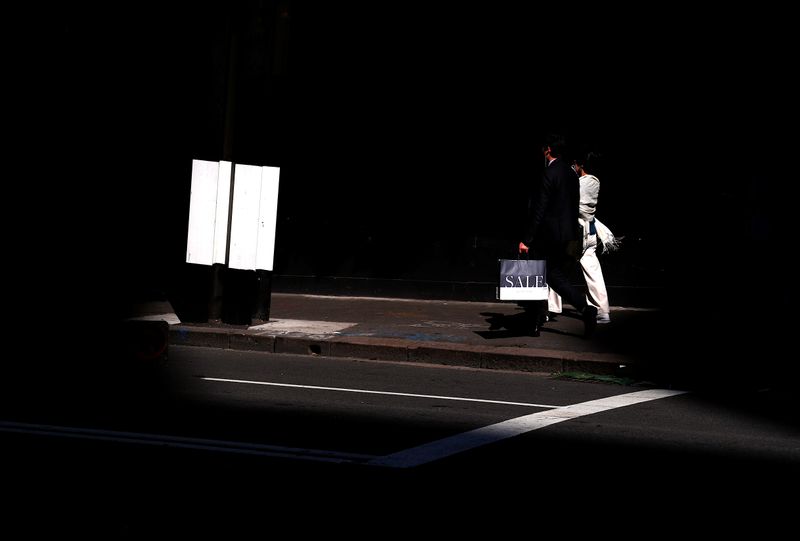 &copy; Reuters. A shopper carries a bag displaying the word &apos;Sale&apos; as he walks along a footpath outside a retail store in central Sydney