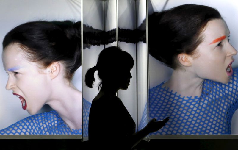 &copy; Reuters. A woman holding her mobile phone walks past a display window outside a cosmetic company at Tokyo&apos;s Ginza shopping district