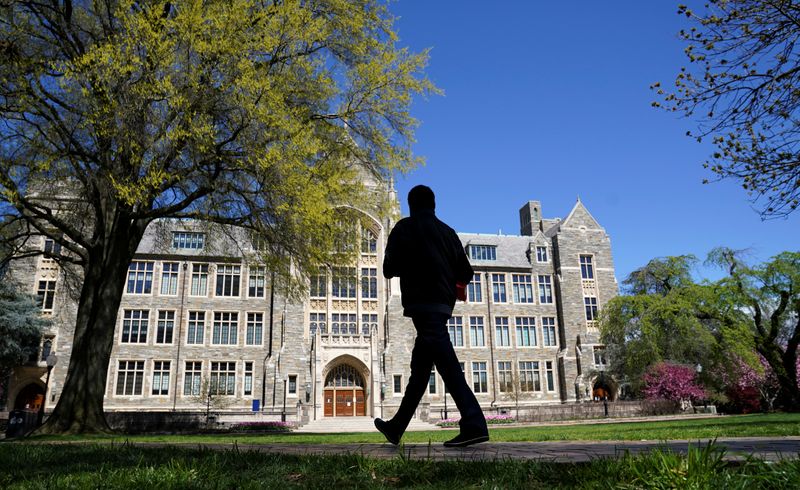 © Reuters. FILE PHOTO: A man walks at an empty campus green at Georgetown University, closed weeks ago due to coronavirus, in Washington