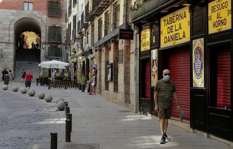 &copy; Reuters. FOTO DE ARCHIVO: Un hombre con mascarilla pasa por un bar cerrado en Madrid, España, el 31 de julio de 2020