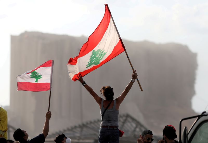 © Reuters. FILE PHOTO: Demonstrators wave Lebanese flags during protests near the site of a blast at Beirut's port area