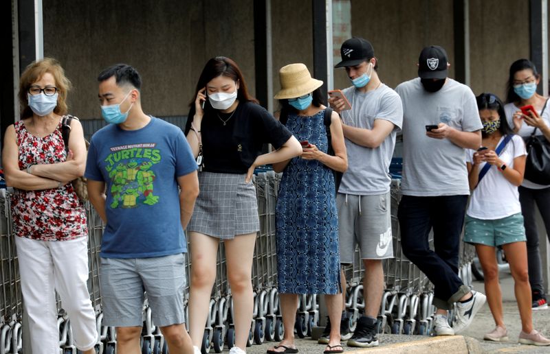 © Reuters. FILE PHOTO: People wear protective face masks outside at a shopping plaza in Edgewater, New Jersey