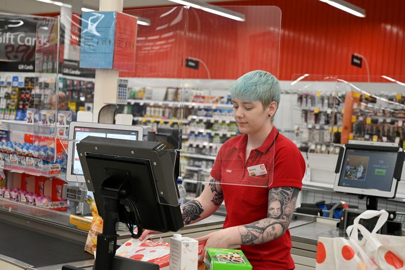 © Reuters. FILE PHOTO: A cashier works behind a protective plexiglass shield at a supermarket in Sydney