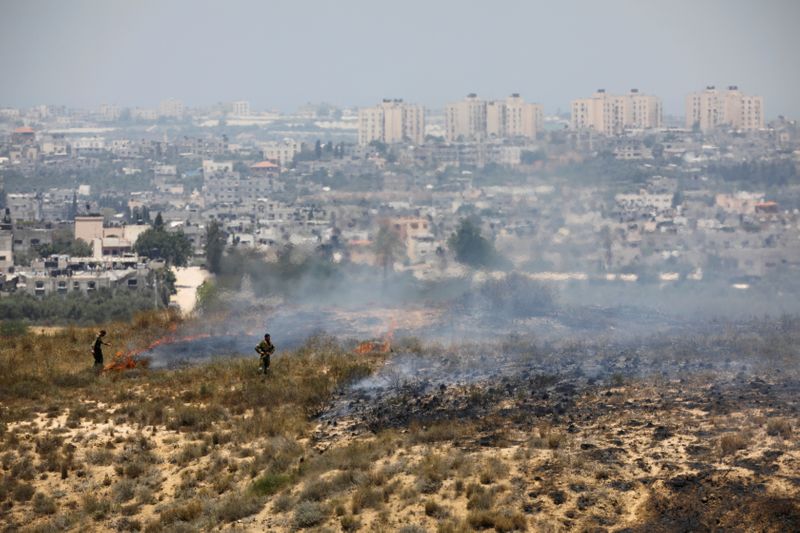&copy; Reuters. FILE PHOTO: Israeli soldiers are seen near fire burns in scrubland near the Gaza Strip, in an area where Palestinians have been causing blazes by flying kites and balloons loaded with flammable material across the border between Israel and the Gaza Strip