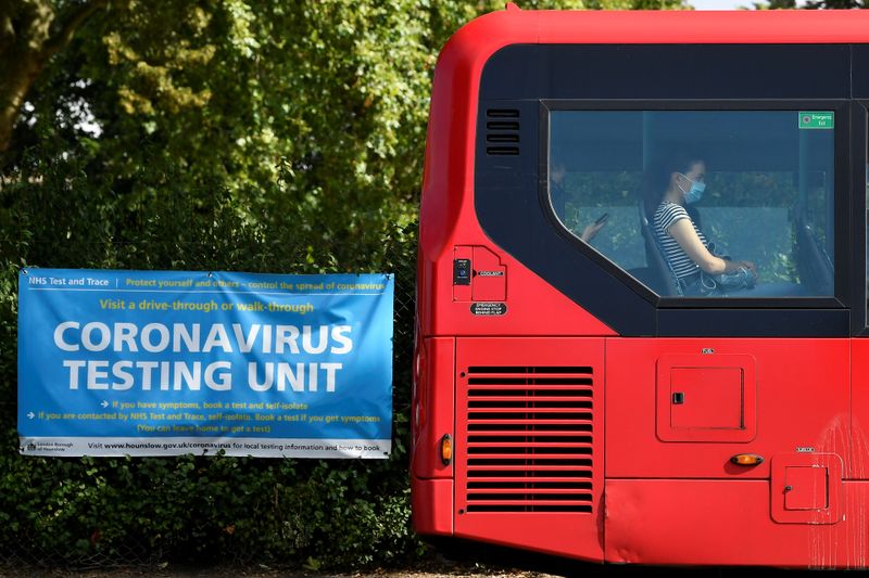 &copy; Reuters. Passageira usa máscara de proteção em ônibus perto de cartas sobre centro de testagem para Covid-19 em Londres