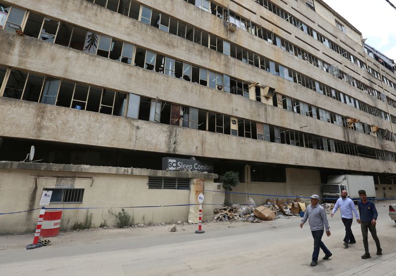 &copy; Reuters. People walk past Sleep Comfort furniture factory that was damaged during Beirut port blast