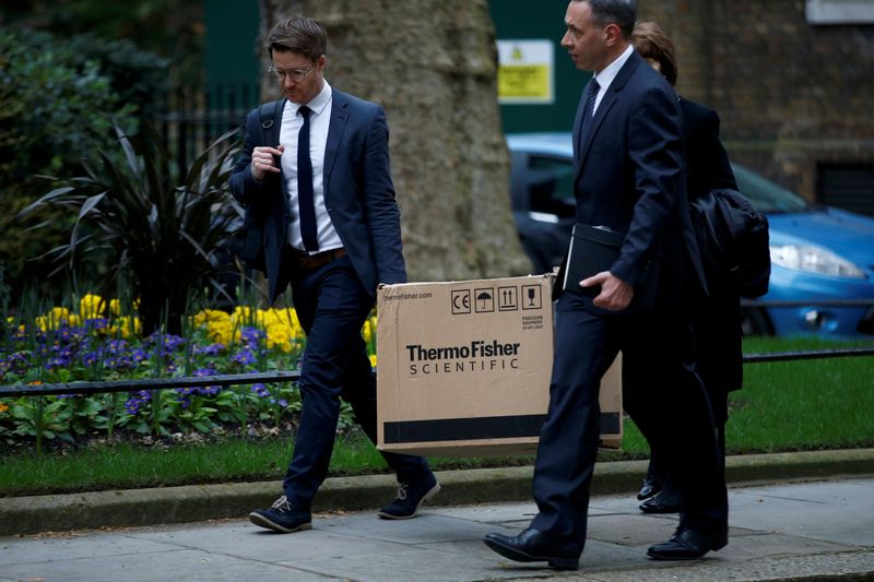 &copy; Reuters. FILE PHOTO: People carrying a box from ThermoFisher Scientific, a company that produces coronavirus tests, walk outside Downing Street in London