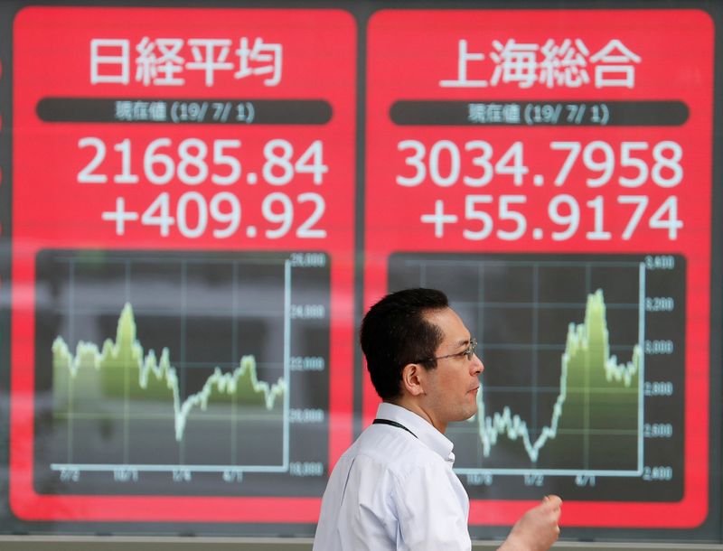 &copy; Reuters. A man walks past an electric screen showing Japan&apos;s Nikkei and Shanghai Stock Exchange markets&apos; indices outside a brokerage in Tokyo