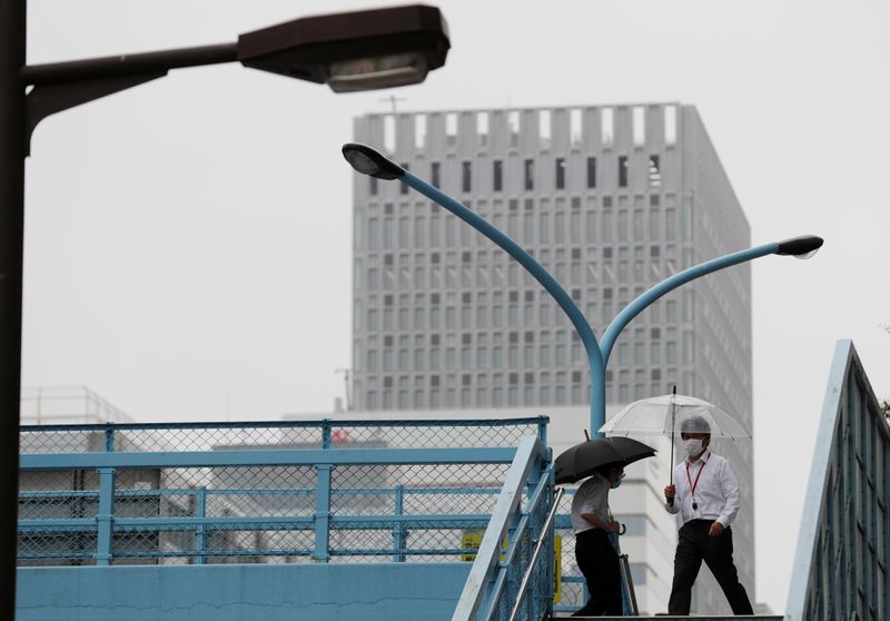 &copy; Reuters. A man wearing a protective face mask, following the coronavirus disease (COVID-19) outbreak, walks on a pedestrian overpass at a business district in Toky