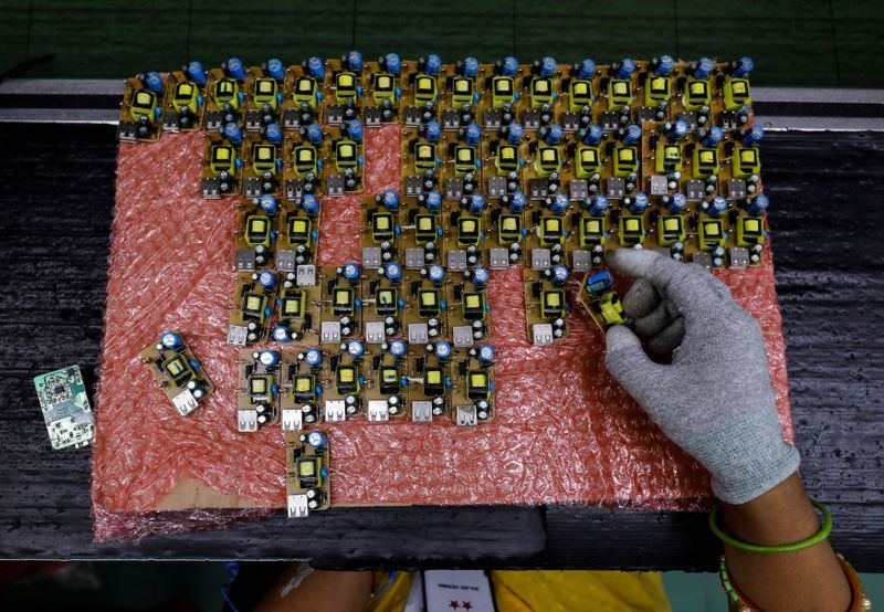 &copy; Reuters. FILE PHOTO: A worker arranges battery charger circuit boards at a mobile phone battery manufacturing plant in Noida