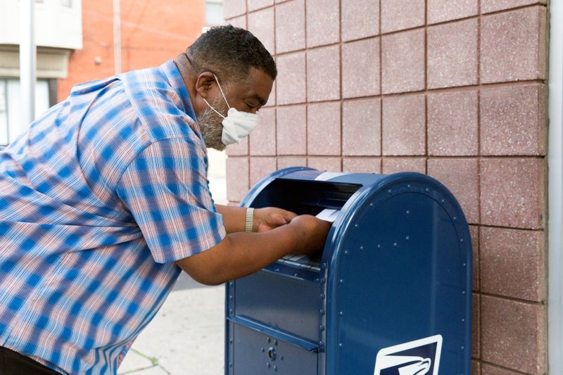 © Reuters. An individual deposits letters into a U.S. Postal Service (USPS) collection mailbox in Philadelphia