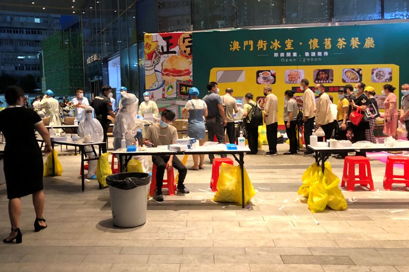 © Reuters. Medical workers wearing protective suits are seen at a nucleic acid testing site outside the IBC Mall in Shenzhen