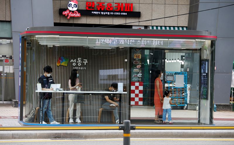 &copy; Reuters. People wait for a bus inside a glass covered stop in Seoul