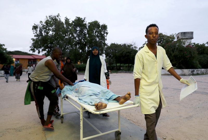 © Reuters. FILE PHOTO: Paramedics and civilians carry an injured person on a stretcher at Madina hospital after a blast at the Elite Hotel in Lido beach in Mogadishu