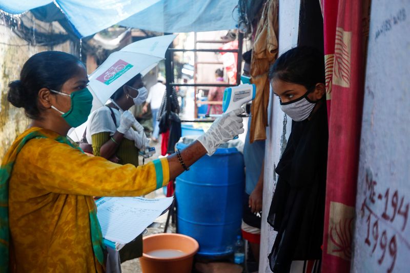 &copy; Reuters. Voluntária que atua na medicina comunitária checa temperatura de garota em favela de Mumbai, na Índia