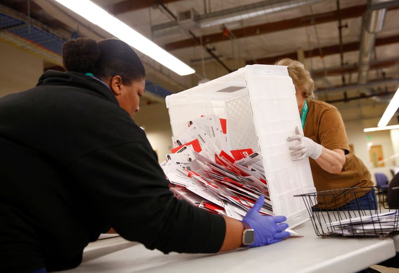 © Reuters. FILE PHOTO: Workers empty a carton of ballots from a drop box to prepare them for the mail sorting machine during the presidential primary at King County Elections ballot processing center in Renton