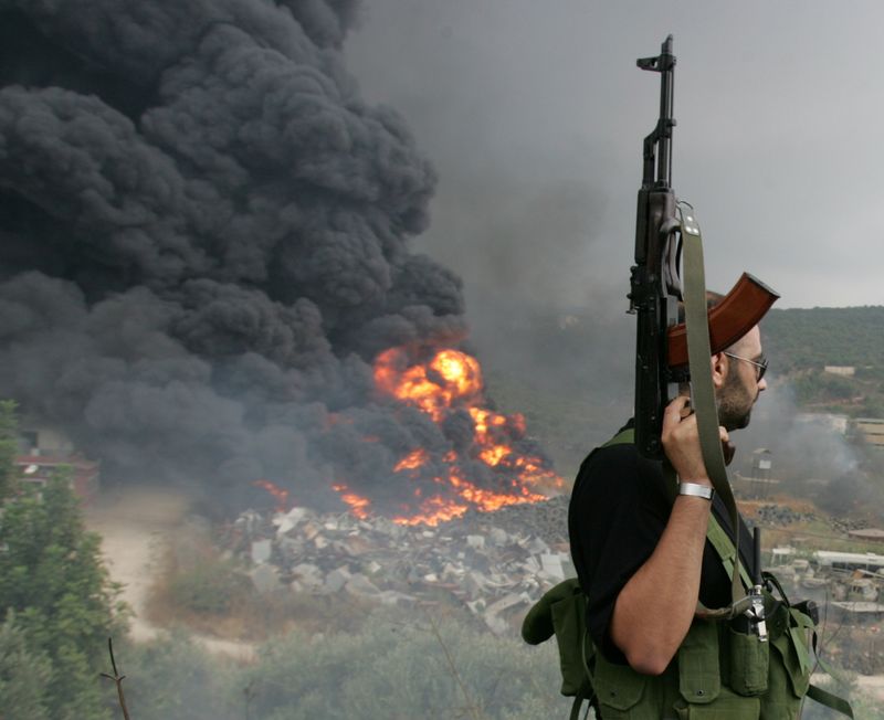 &copy; Reuters. FILE PHOTO: A Lebanese Hezbollah guerrilla looks at a fire rising from a burning object in a Beirut suburb