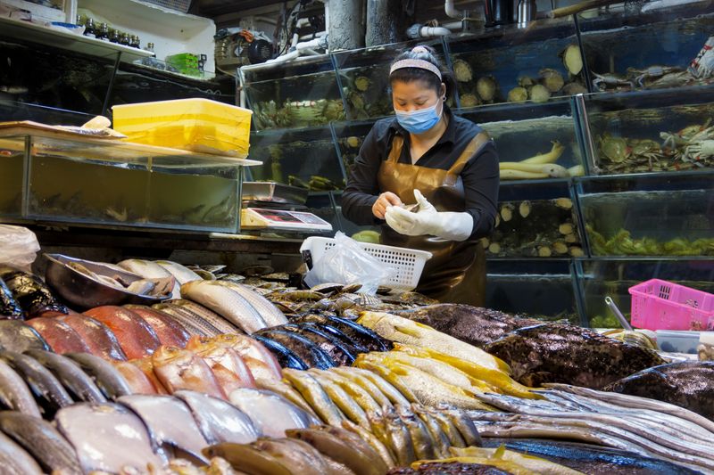 &copy; Reuters. FOTO DE ARCHIVO: Una mujer trabaja en un puesto de pescados y mariscos de un mercado de Pekín, China