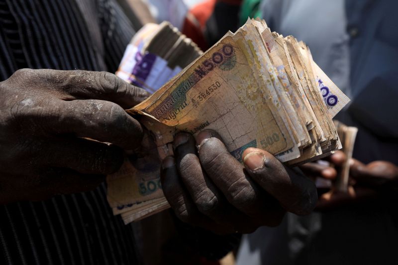 &copy; Reuters. FILE PHOTO: Man carries Nigerian naira banknotes at a livestock market in Abuja
