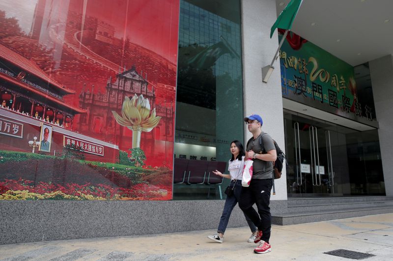 &copy; Reuters. FILE PHOTO: People walk past the headquarters building of Luso International Banking Ltd. in Macau