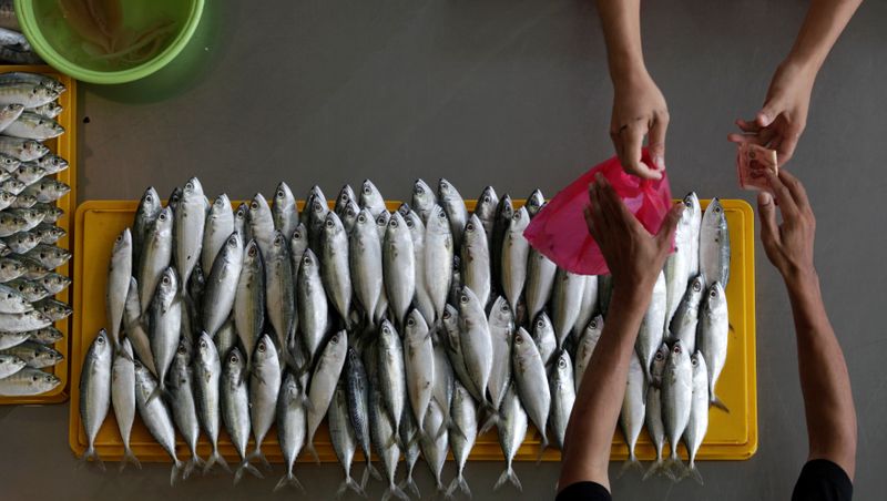 &copy; Reuters. A fishmonger makes a sale at a market in Kuala Lumpur