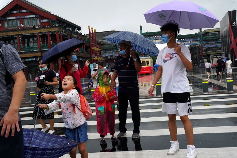 © Reuters. People wearing face masks walk near Qianmen Street on a rainy day, following the coronavirus disease (COVID-19) outbreak, in Beijing