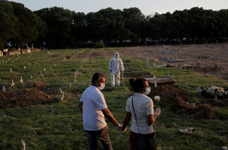 &copy; Reuters. Casal em cemitério no Rio de Janeiro durante enterro de pessoa que morreu de causas desconhecidas durante a pandema de Covid-19