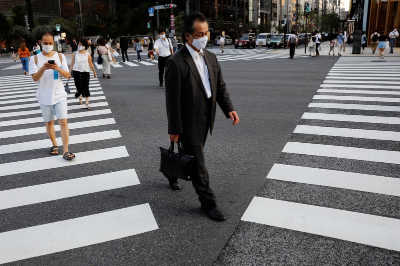 © Reuters. People wearing protective masks make their way at a business district in Tokyo