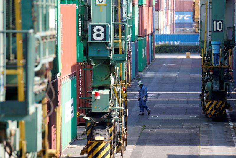 &copy; Reuters. FILE PHOTO: A worker walks between shipping containers at a port in Tokyo, Japan