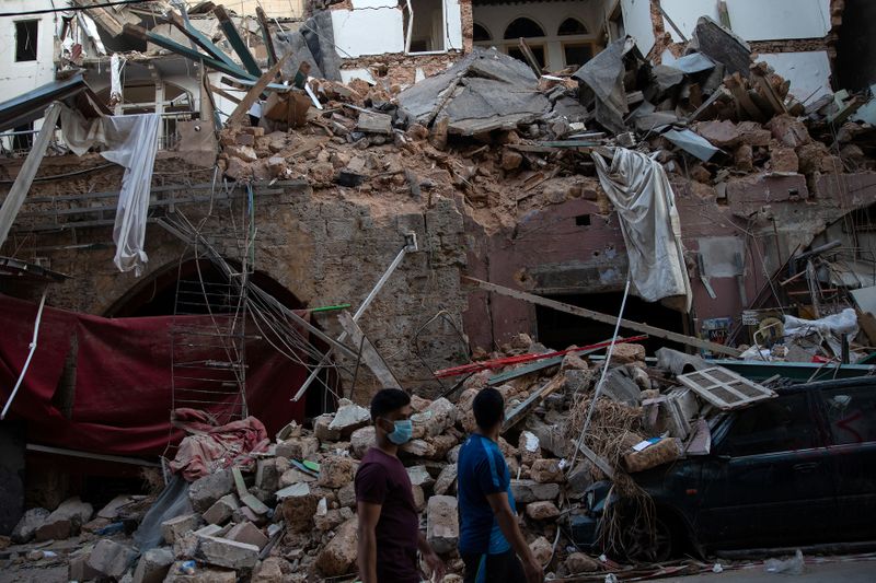 © Reuters. People walk past destroyed traditional Lebanese houses, following a massive explosion at the port area, in Beirut