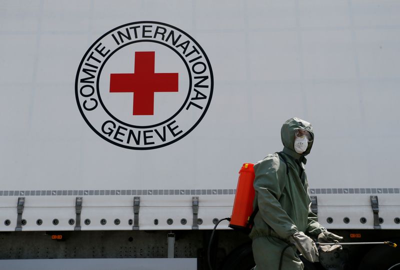 &copy; Reuters. Agente com roupa de proteção desinfecta caminhão em ponto de checagem do Comitê Internacional da Cruz Vermelha em Donetsk